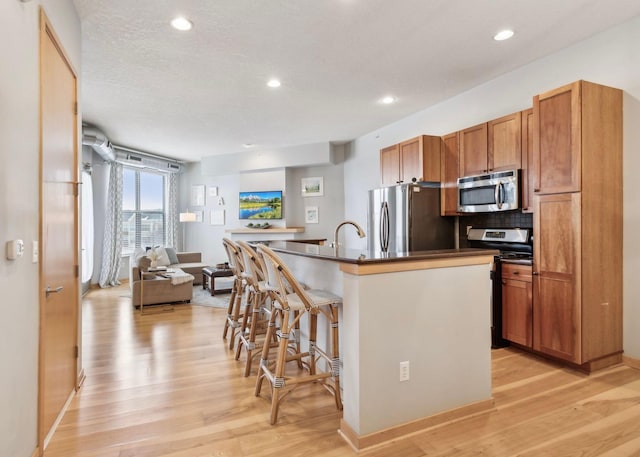 3640 Wooddale Ave S Unit 317, Saint Louis Park, MN 55416 - kitchen featuring appliances with stainless steel finishes, a breakfast bar, light wood-style floors, dark countertops, and recessed lighting