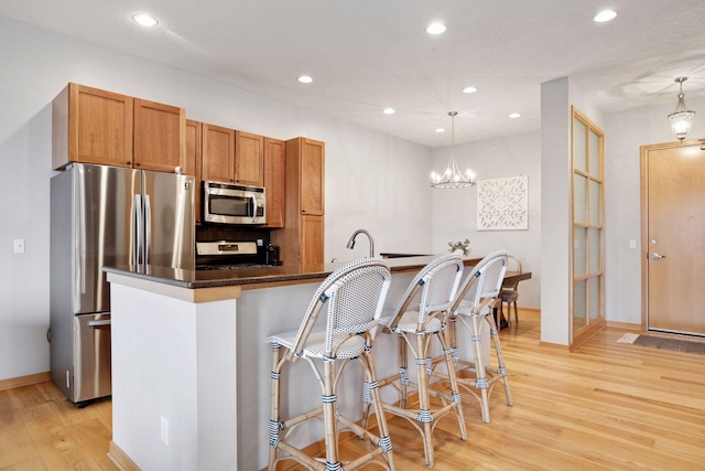 3640 Wooddale Ave S Unit 317, Saint Louis Park, MN 55416 - kitchen featuring appliances with stainless steel finishes, light wood-style floors, recessed lighting, brown cabinets, and a kitchen breakfast bar