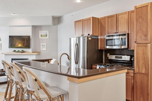 3640 Wooddale Ave S Unit 317, Saint Louis Park, MN 55416 - kitchen featuring stainless steel appliances, a breakfast bar, dark countertops, brown cabinets, and backsplash