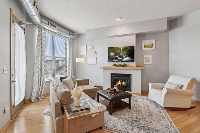 3640 Wooddale Ave S Unit 317, Saint Louis Park, MN 55416 - living room featuring a glass covered fireplace, wood finished floors, a textured ceiling, and baseboards