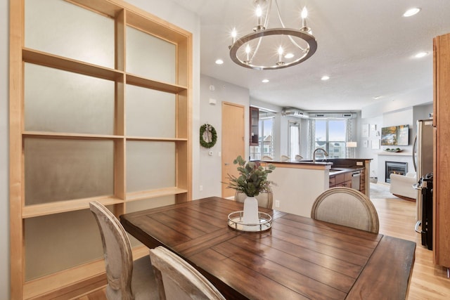 3640 Wooddale Ave S Unit 317, Saint Louis Park, MN 55416 - dining area featuring a chandelier, light wood-style flooring, recessed lighting, and a lit fireplace