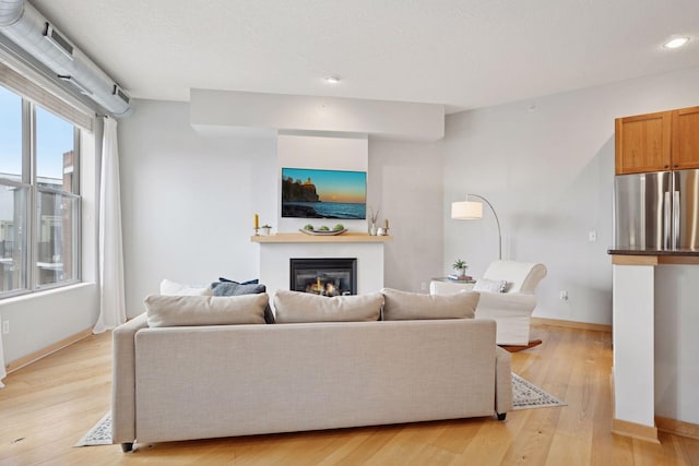 3640 Wooddale Ave S Unit 317, Saint Louis Park, MN 55416 - living room featuring a glass covered fireplace, baseboards, light wood-style floors, and recessed lighting