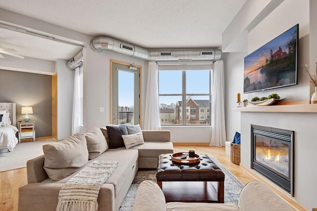 3640 Wooddale Ave S Unit 317, Saint Louis Park, MN 55416 - living area with light wood-type flooring, a glass covered fireplace, a ceiling fan, a textured ceiling, and baseboards