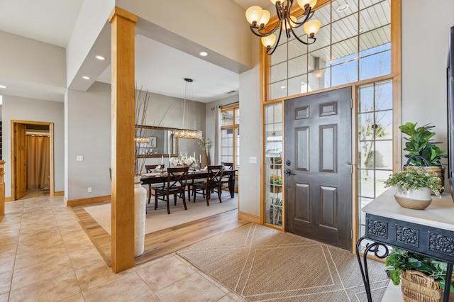 tiled entryway featuring an inviting chandelier, baseboards, a high ceiling, and recessed lighting