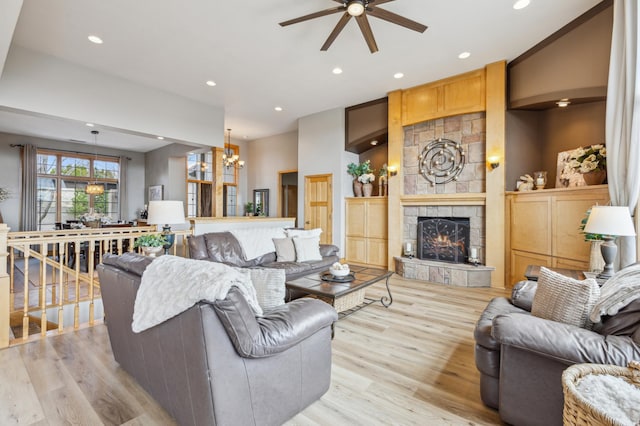living room with light wood-style floors, recessed lighting, ceiling fan with notable chandelier, and a fireplace