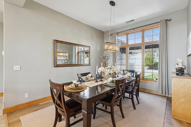 dining area with baseboards, visible vents, and light wood-type flooring