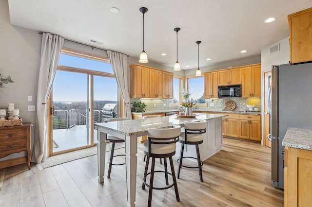 kitchen featuring visible vents, freestanding refrigerator, backsplash, and black microwave