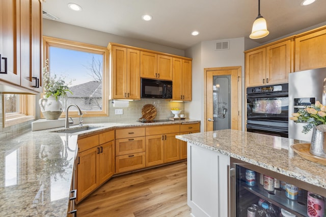 kitchen featuring visible vents, light wood-style floors, a sink, backsplash, and black appliances