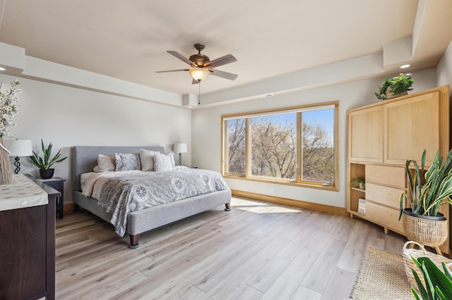 bedroom with a ceiling fan, baseboards, and light wood finished floors