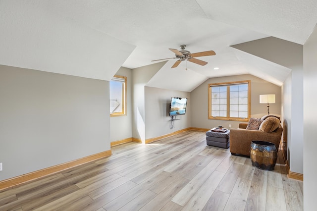 additional living space with a ceiling fan, baseboards, lofted ceiling, and light wood-style floors