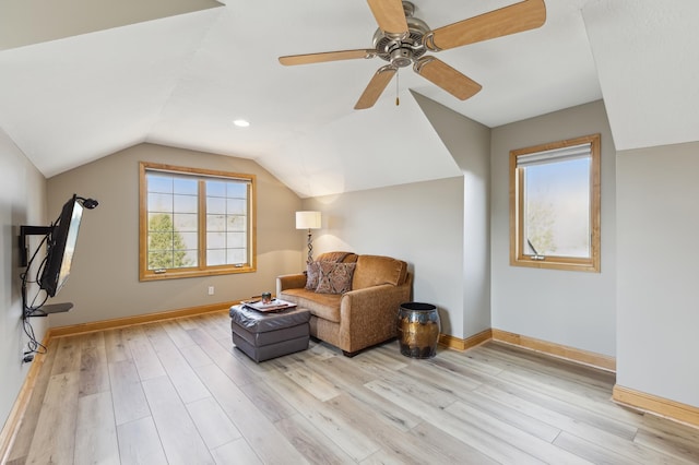 sitting room with baseboards, ceiling fan, light wood-style flooring, and lofted ceiling