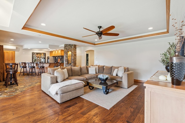 living area featuring ceiling fan, dark wood-type flooring, recessed lighting, a tray ceiling, and arched walkways