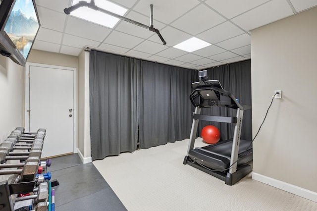 exercise room featuring baseboards and a drop ceiling