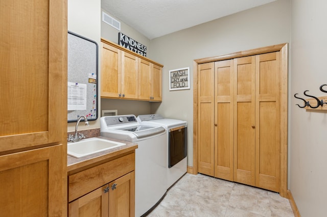 laundry area with visible vents, washing machine and dryer, cabinet space, a sink, and baseboards
