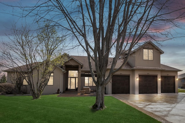 view of front of property featuring a garage, a front lawn, stucco siding, and driveway