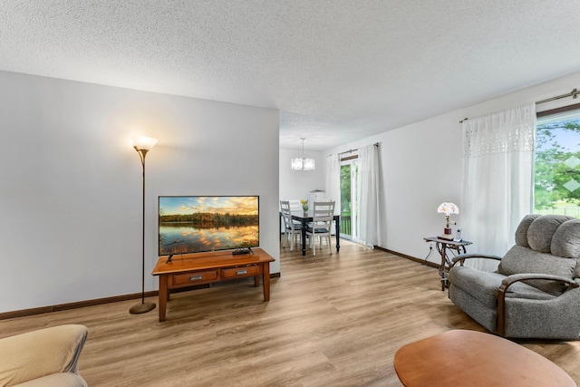 216 Richard Ave SE, Isanti, MN 55040 - living room with light wood-type flooring, a chandelier, a textured ceiling, and baseboards