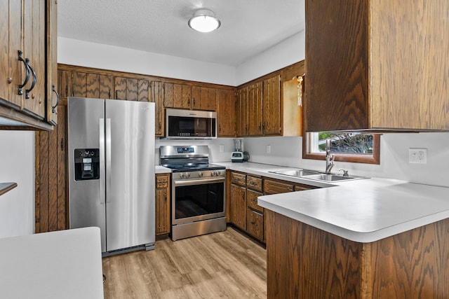 216 Richard Ave SE, Isanti, MN 55040 - kitchen featuring stainless steel appliances, a sink, light countertops, light wood finished floors, and a peninsula