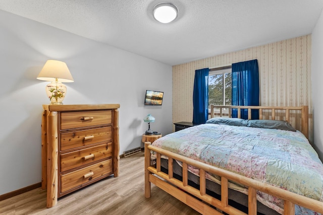 216 Richard Ave SE, Isanti, MN 55040 - bedroom featuring wallpapered walls, light wood-type flooring, a textured ceiling, and baseboards
