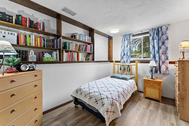 216 Richard Ave SE, Isanti, MN 55040 - bedroom with baseboards, light wood-style floors, and a textured ceiling