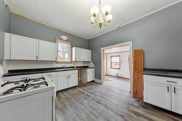 107 6th Ave SE, Waseca, MN 56093 - kitchen featuring dark wood-style flooring, white range with gas stovetop, white cabinets, a sink, and a notable chandelier