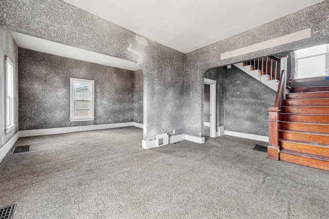 107 6th Ave SE, Waseca, MN 56093 - unfurnished living room with stairs, arched walkways, visible vents, and carpet