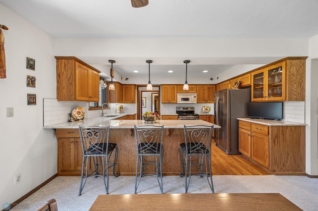 kitchen with brown cabinets, a sink, stainless steel appliances, a peninsula, and glass insert cabinets