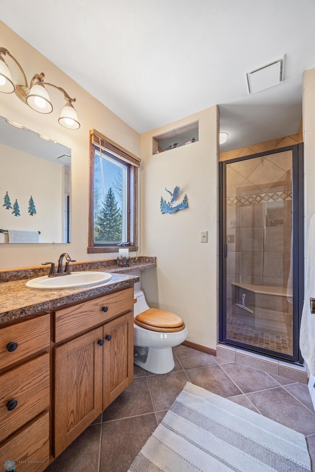 bathroom featuring a stall shower, vanity, tile patterned floors, baseboards, and toilet