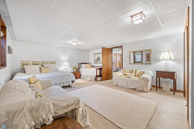 bedroom with baseboards, a drop ceiling, and wood finished floors