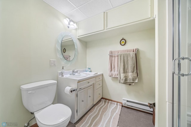 bathroom with vanity, baseboard heating, a drop ceiling, and toilet