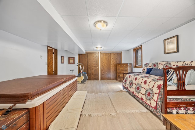 bedroom with light wood-type flooring and a paneled ceiling