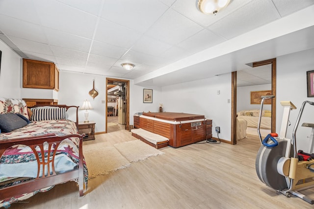 bedroom featuring baseboards, light wood-style flooring, and a drop ceiling