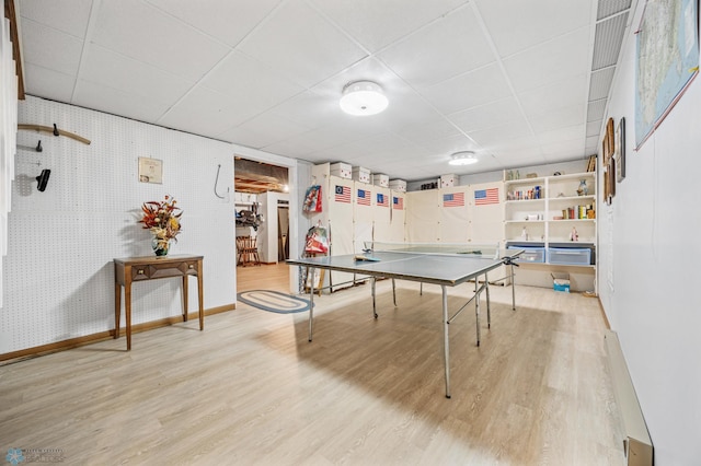 recreation room with baseboards, wood finished floors, and a paneled ceiling