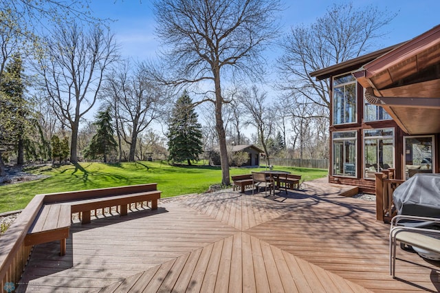 deck with a sunroom, an outbuilding, outdoor dining area, and a yard