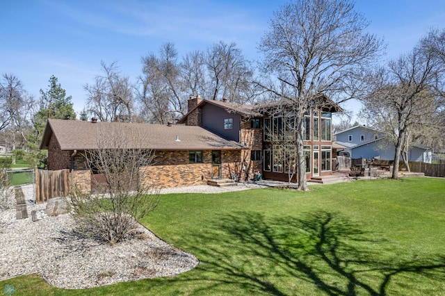 back of property featuring a yard, fence, a chimney, and a sunroom