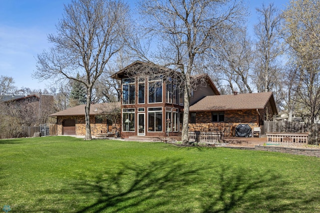 back of property featuring a lawn, fence, an attached garage, and a sunroom