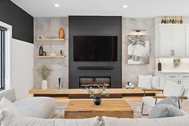 living area featuring recessed lighting, light wood finished floors, and a fireplace