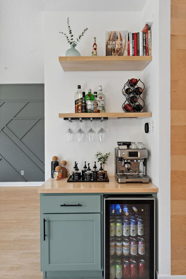 bar featuring a bar, wine cooler, and light wood-type flooring