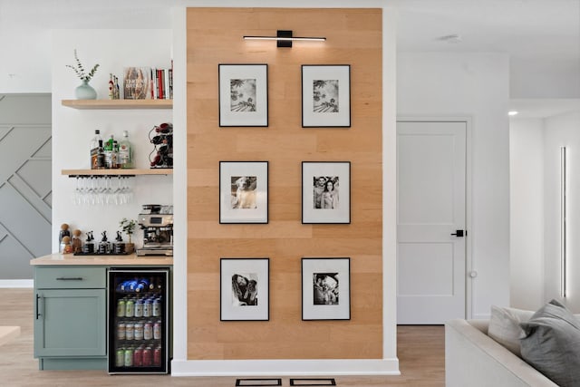 bar featuring a bar, light wood-style flooring, and beverage cooler