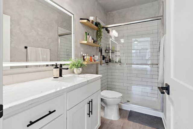 full bath featuring vanity, toilet, wood finished floors, and a stall shower