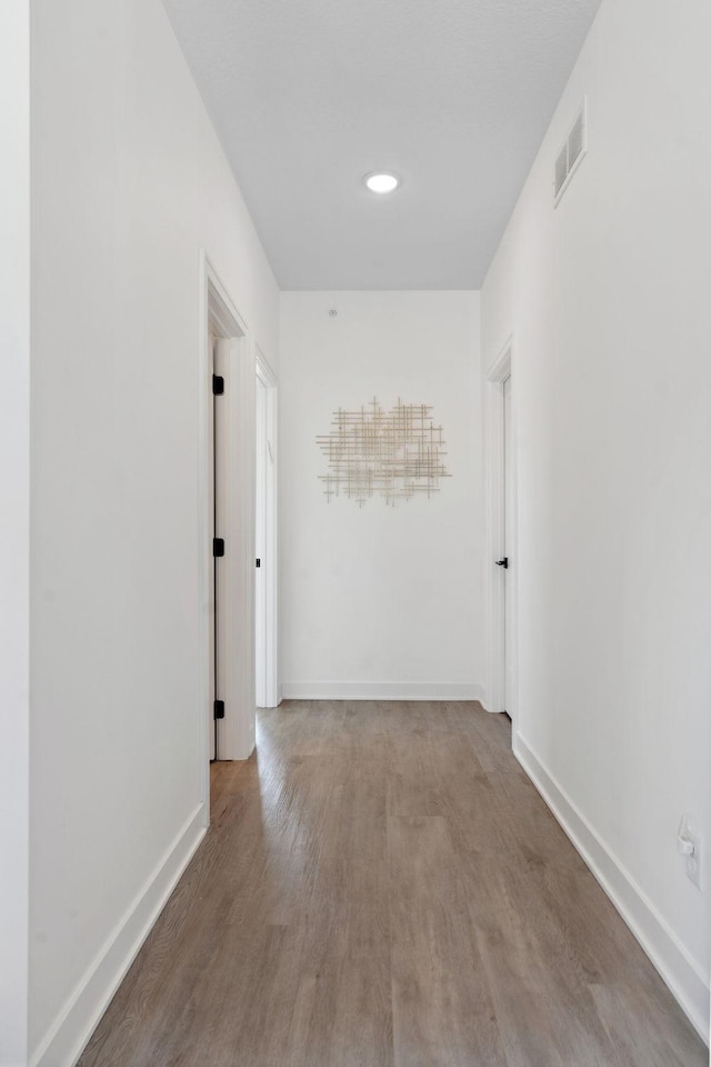 corridor with visible vents, baseboards, and wood finished floors
