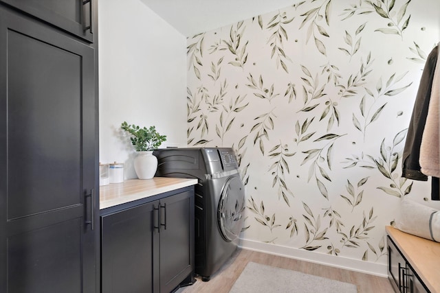 laundry area featuring light wood-type flooring, cabinet space, and baseboards