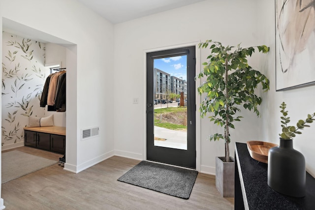 foyer entrance featuring light wood-style floors, baseboards, and visible vents