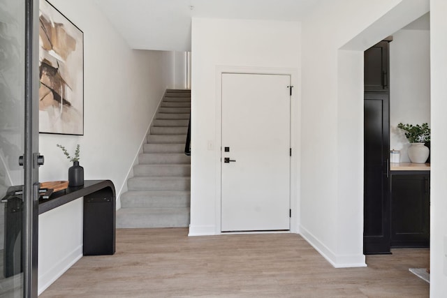 entrance foyer featuring light wood-type flooring, stairs, and baseboards