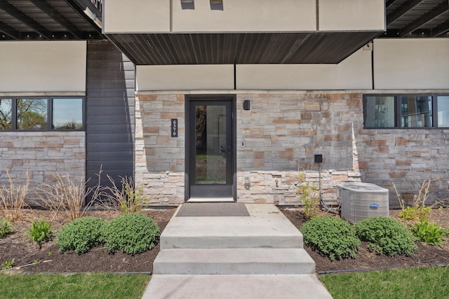entrance to property with cooling unit and stone siding