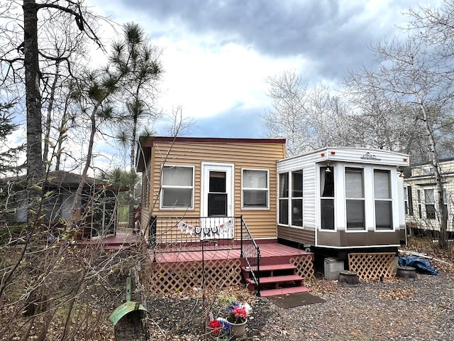 rear view of property featuring a wooden deck and a sunroom