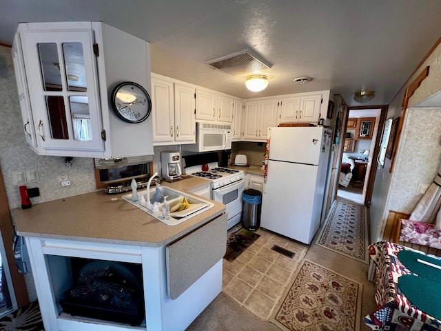 kitchen featuring white appliances, white cabinets, and light countertops