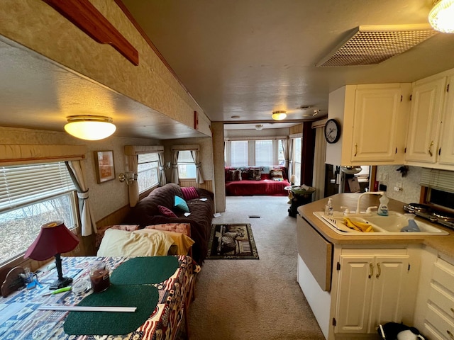 kitchen with open floor plan, carpet floors, white cabinets, and healthy amount of natural light