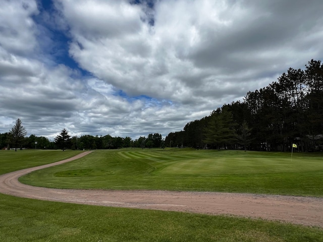 surrounding community featuring view of golf course, a lawn, and an area to practice putting