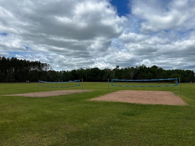 surrounding community featuring volleyball court, a lawn, and a view of trees