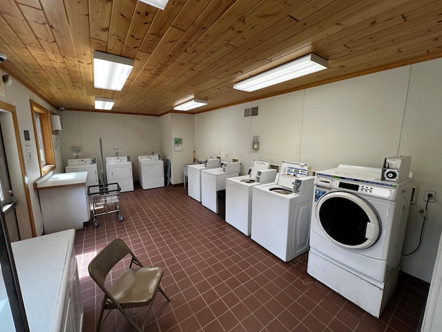shared laundry with washing machine and dryer, wooden ceiling, and dark tile patterned flooring